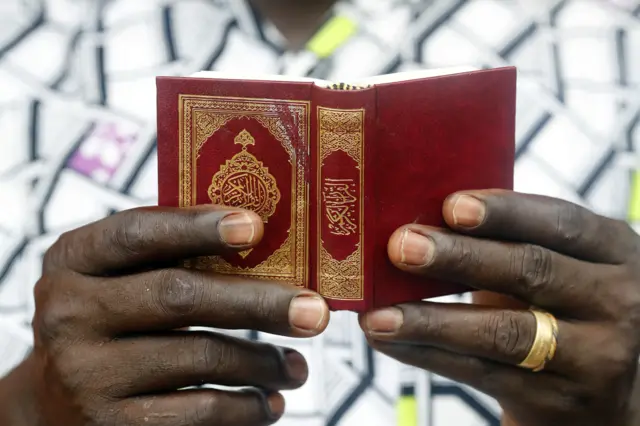 A man reading a small Quran in West Africa.