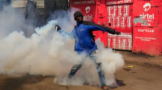 A protestor hurls a tear gas canister