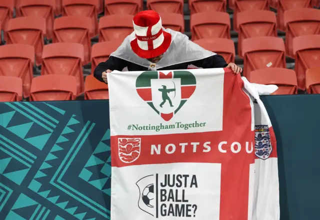 An England fan hangs up a banner with their club team Notts County on it.