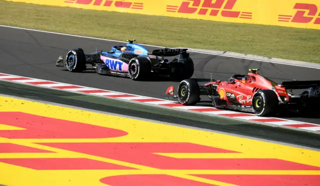 Pierre Gasly (L) and Carlos Sainz race their F1 cars on the track