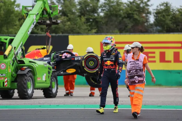 Sergio Perez walks away from the wreckage of his Red Bull with a marshal