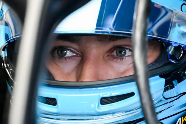 George Russell wears a bright blue crash helmet with his eyes visible in his visor