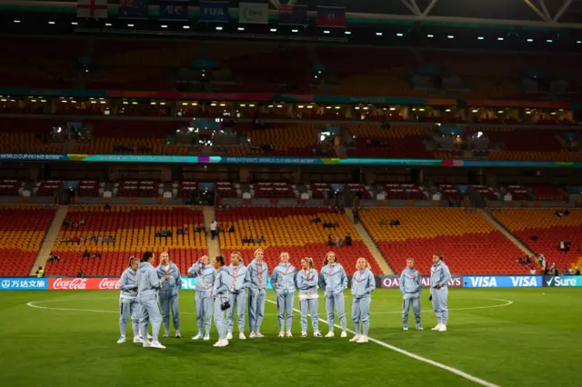 England players stand in the centre circle as they survey the playing surface.