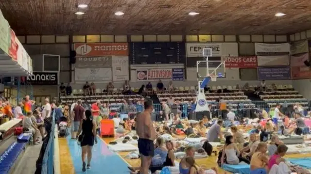 Tourists shelter on an indoor basketball court following wildfires on the island of Rhodes