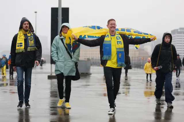 A Sweden fan holds aloft a scarf as he walks to the stadium.