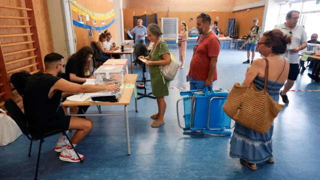 Monica Lopez and her husband carry beach chairs as they cast their votes during a general snap election at a polling station in Barcelona, Spain