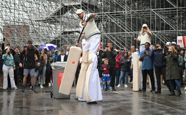 A fan on stilts using a giant bat defends a ball at Old Trafford