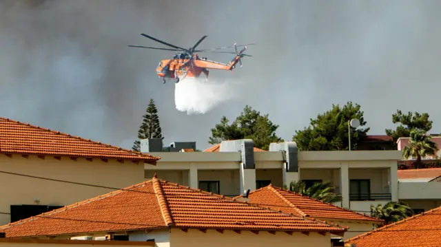 A firefighting aircraft drops water to extinguish a wildfire in Kiotari village, on Rhodes island