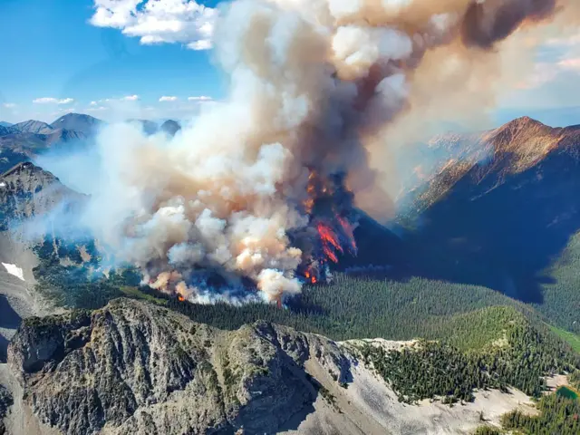 Smoke rises from a wildfire in the mountains