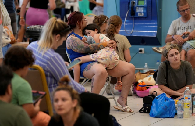 Tourists wait for departing planes at the airport, after being evacuated following a wildfire on the island of Rhodes