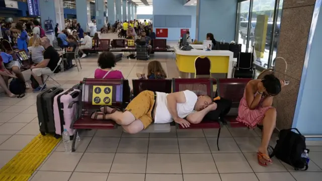 Passengers - including one man asleep - in an airport terminal on the Greek island of Rhodes