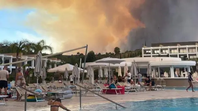 A huge cloud of smoke goes up over a busy hotel