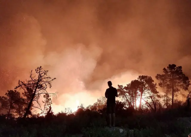 Man stands in front of wildfire