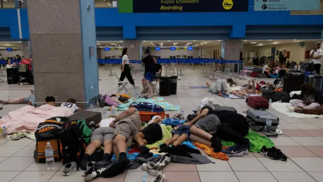 Tourists sleep as they wait for departing planes at the airport on Rhodes