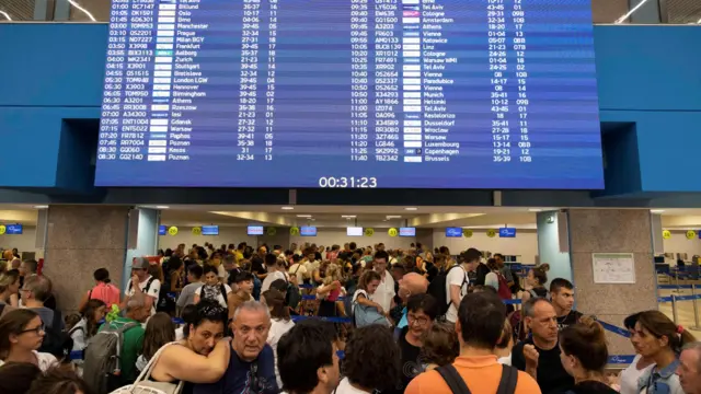 Tourists line up at check-in counters as they wait for departing planes at the airport