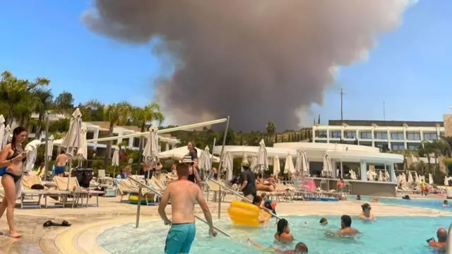 A huge cloud of smoke goes up over a busy hotel