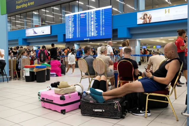 Tourists sitting on chairs at Rhodes airport