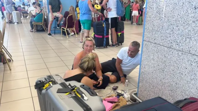 Squirrell family sitting on the floor of Rhodes airport, next to their luggage