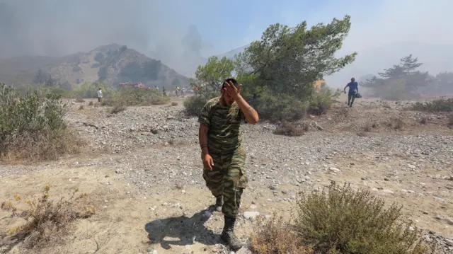 A volunteer reacts as a wildfire burns near the village of Vati, on the island of Rhodes, Greece