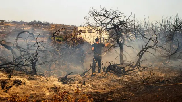 A firefighter tries to put out a wildfire in Kiotari village