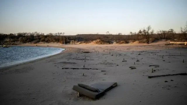 A sunbed mattress is seen at a burnt down beach bar destroyed by wildfires at the beach of Glystra