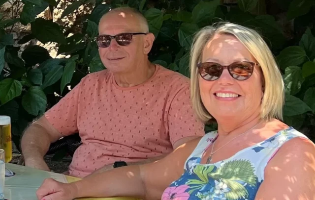 A man wearing glasses sits next to a woman wearing glasses