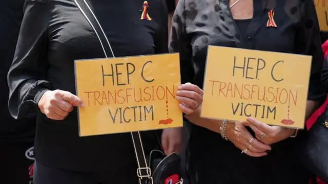 Campaigners hold signs reading: "Hep C Transfusion Victim"