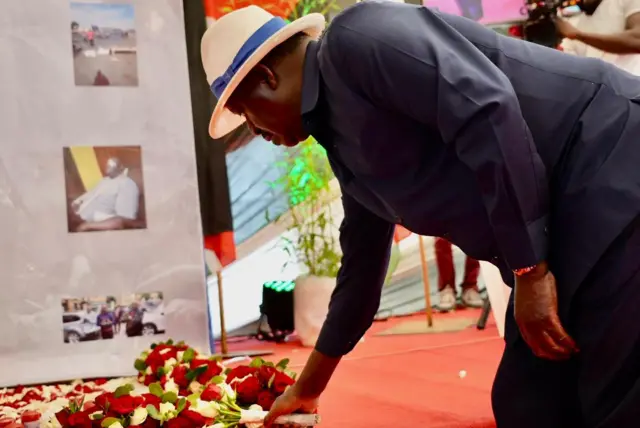 Kenya's opposition leader Raila Odinga laying flowers at a memorial site where pictures of some of deceased protestors were displayed.