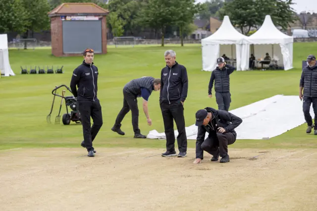 Umpires assess the wicket at Goldenacre