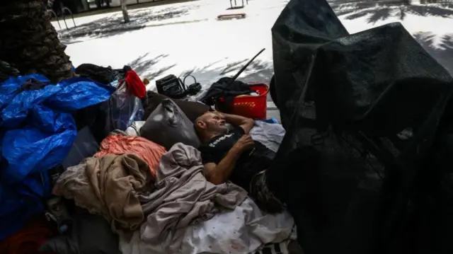 A person experiencing homelessness rests among their belongings during a heatwave in Miami