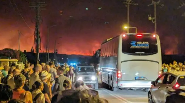 Tourists waiting on the site of the road as wildfires hit the Greek island of Rhodes this week