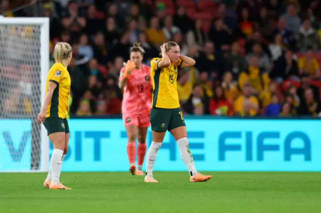 Australia players stand stunned after they concede an equaliser just before half time.