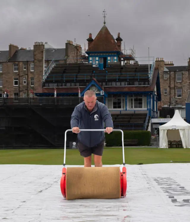 A groundsman works on the wicket