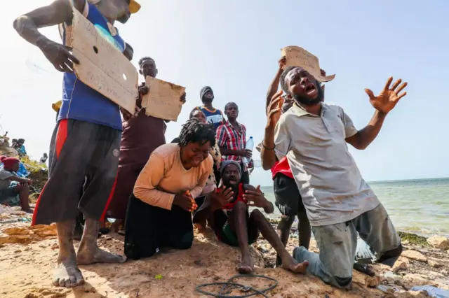 Stranded African migrants plead to be saved from a desert zone between Libya and Tunisia on July 26