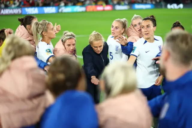 England players gather around to listen to coach Sarina Wiegman.