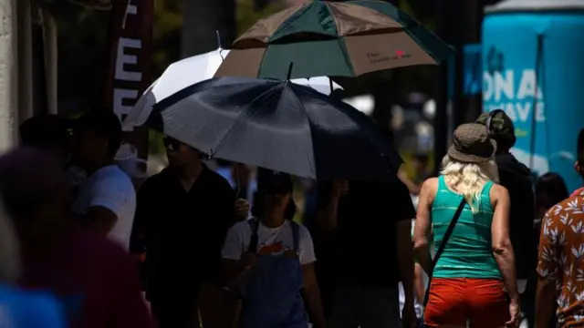 People use umbrellas to protect themselves from the sun during a heatwave at Echo Par