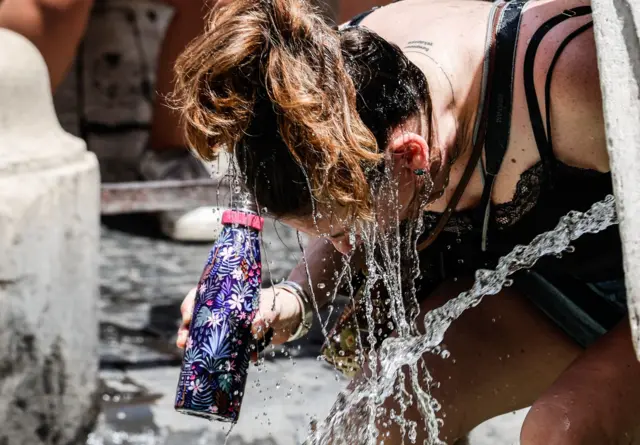 A person pours water to cool off amid high temperatures in Rome