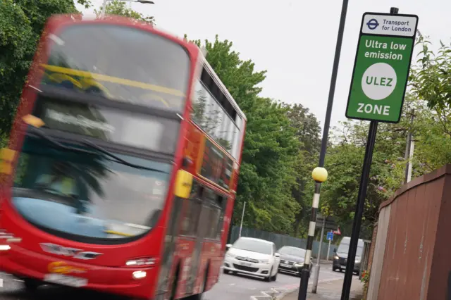 A London bus drives past a Ulez sign