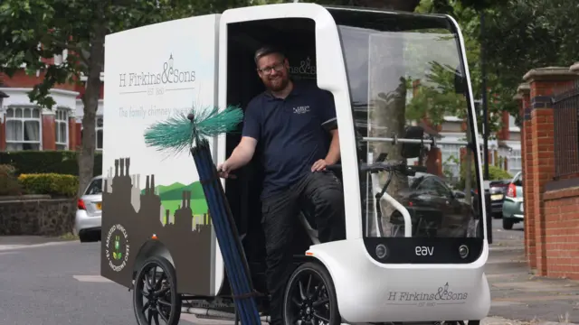 Josh holds his sweep while in an electric van