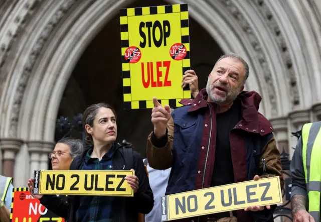 Protesters outside the High Court hold "no to Ulez" signs