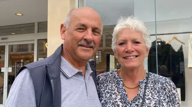 Nigel and Pat smiling outside a store