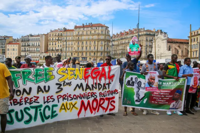 Protesters hold banners during the demonstration against the dictatorship of Senegalese President Macky Sall.