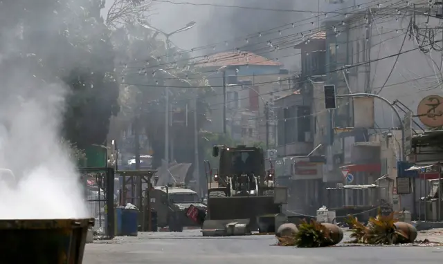 An Israeli army bulldozer and armoured vehicle make their way through Jenin