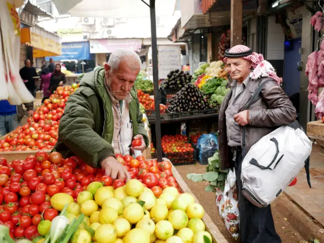 A man seen picking up tomatoes at a local market in Jenin