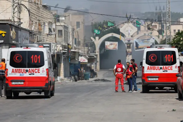 Palestinian medics stand by as smoke rises during an Israeli military operation in Jenin