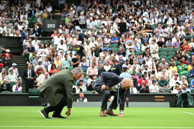 Officials check the Centre Court turf