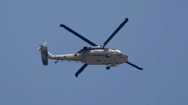 An Israeli military helicopter flies over the Jalameh crossing leading to the West Bank