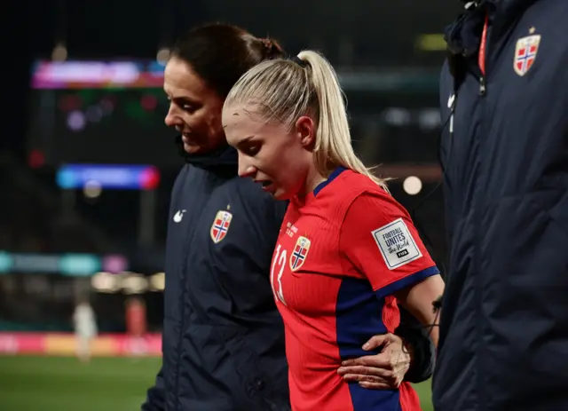 Bjelde is helped off the pitch by two medics.