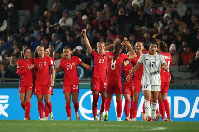 Norway players celebrate as a Philippines defender looks fed up in front of them.