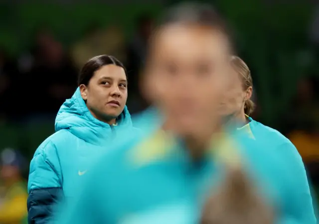 Sam Kerr watches on as her teammates warm up.